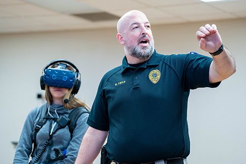 Captain Matt Swain demonstrates a verbal de-escalation tactic during an on-campus training with students