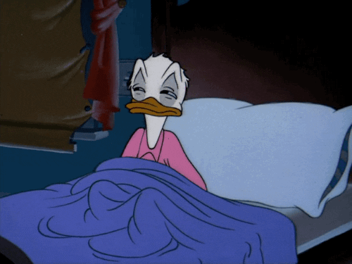 Donald Duck pulls a blanket over his head while laying in bed.
